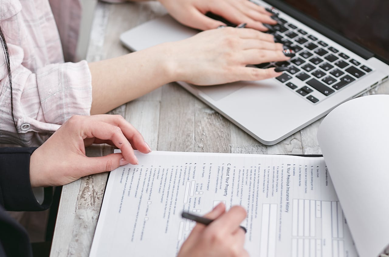 Mastering the First Impression: Your intriguing post title goes here Close-up of hands typing on a laptop and reviewing business documents, focused on finance and legal tasks.